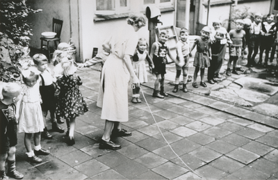876961 Afbeelding van een grote groep kleuters die toekijkt bij het touwtjespringen op de binnenplaats van het Klooster ...